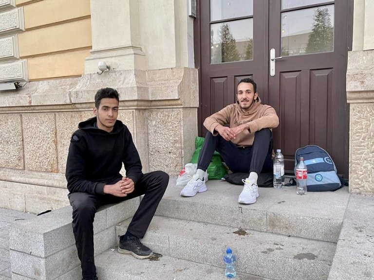Osman, 20 ans, et Mohsen, 26 ans, tuent le temps devant la gare désaffectée de Belgrade. Bientôt, ils prendront le bus pour le nord du pays. Crédit : InfoMigrants
